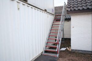 Foto van een verdiepingstrap met bordes die aan een 20ft zeecontainer is bevestigd.