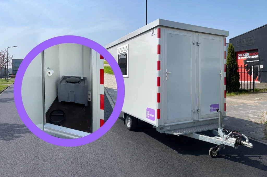 Interior of a portable toilet trailer showing a grey toilet with black lid and a wall-mounted toilet paper roll inside a small cubicle